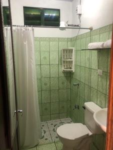 Baño de azulejos verdes con aseo y lavamanos en Apartamento BYES en Quepos