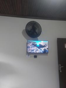 a television on a wall with a basket on the wall at Sobrado Flor de Maio in Milho Verde