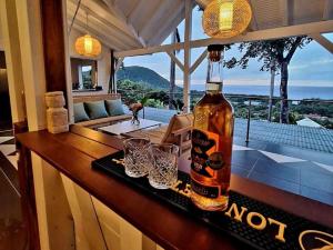 a bottle of alcohol sitting on a bar with glasses at Villa Calysta in Deshaies