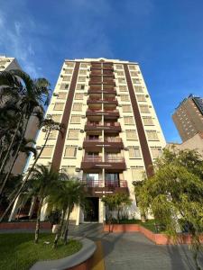 een hoog gebouw met palmbomen ervoor bij Apê aconchegante e perto de tudo in Guarujá