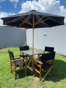 une table en bois avec deux chaises et un parasol dans l'établissement Casa com ótima localização, à Foz do Iguaçu