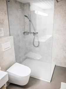 ein weißes Bad mit einer Dusche und einem WC in der Unterkunft Chalet Lilo 4 Zimmer big view in Beatenberg