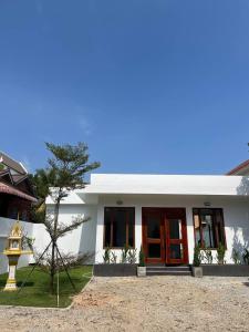 a white house with red doors and a yard at UMA Residence in Siem Reap