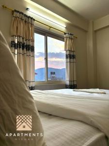 - une chambre avec un lit et une grande fenêtre dans l'établissement Nishan Apartments -Lakeside, à Pokhara