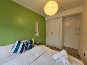 a bedroom with a white bed with a green wall at London Mile End Rooms in London