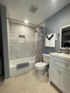 a bathroom with a tub and a toilet and a sink at Cozy Home w/Deck & Fire Pit! in Greensboro