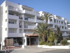 um edifício branco com palmeiras em frente em Apartamento Roses, 1 dormitorio, 4 personas - ES-258-117 em Roses