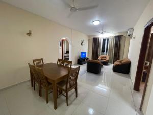 Wellawatte Apartments في كولومبو: غرفة معيشة مع طاولة وكراسي خشبية