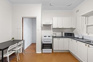 a kitchen with white cabinets and a black counter top at Cozy Lindfield Stayz in Sydney