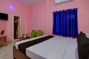 a bedroom with a large bed with blue curtains at Khushi Guest House in Bhubaneshwar