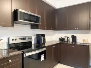 a kitchen with brown cabinets and a stove and microwave at Dockside Relaxing Private Bedroom,, in Whitby