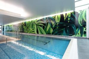 uma piscina com um mural de plantas na parede em The Grand by SkyCity em Auckland