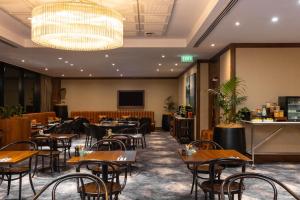 a restaurant with tables and chairs and a chandelier at The Grand by SkyCity in Auckland