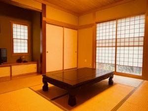 a room with a table in a room with windows at mimo’s cottage 斑尾山麓の庭付き貸切コテージ タングラムスキー場リフト乗場まで徒歩5分 in Madarao Kogen