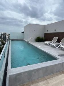 a swimming pool on top of a building with chairs at Oxygen! beautiful beach apartament 1BR Ocean view in Playa del Carmen