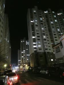 miasto nocą z samochodami zaparkowanymi przed wysokimi budynkami w obiekcie Moslim friendly guest house w mieście Yangsan