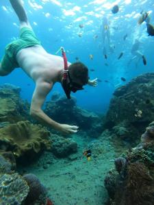 un hombre nadando en el agua cerca de un arrecife en D'Waktu in House, en Nusa Lembongan
