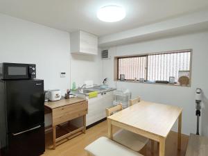 芙蓉居 日本庭園付き一戸建 【天下茶屋から徒歩8分】最大6名宿泊可能 في أوساكا: مطبخ مع طاولة وثلاجة سوداء