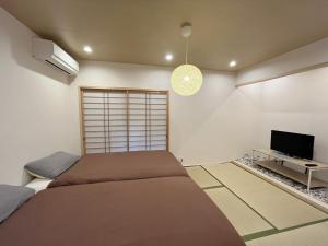 芙蓉居 日本庭園付き一戸建 【天下茶屋から徒歩8分】最大6名宿泊可能 في أوساكا: غرفة نوم بسرير وتلفزيون بشاشة مسطحة