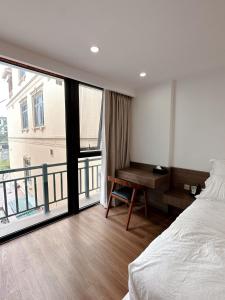 a bedroom with a bed and a desk and a balcony at TINH ANH HOME in Hanoi