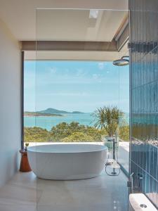 a bath tub in a bathroom with a large window at Casa Alma by Elite Havens in Nai Harn Beach