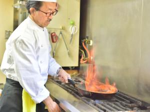 a chef cooking food in a pan on a grill at Petit Hotel Kanan in Chino