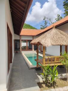 a villa with a swimming pool and a straw umbrella at Vera Koe in Kuta Lombok