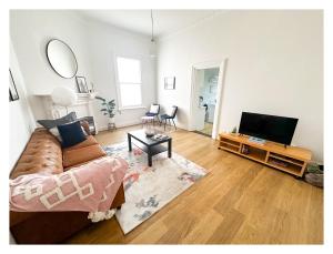 uma sala de estar com um sofá e uma televisão de ecrã plano em HAVEN: Stunning Unley *history*location*charm 3bd em Unley
