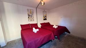 two beds in a room with red sheets and towels at CASA MAGNOLIA in Guatemala