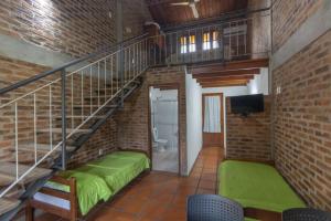 a living room with a staircase and a green bed at Hostal Canela in Termas del Daymán