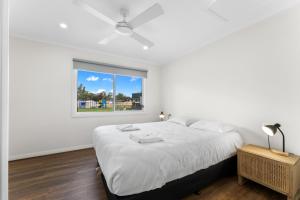 a white bedroom with a large bed and a window at Waikerie Holiday Park in Waikerie