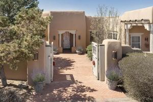a house with a driveway with a gate and trees at Villa Namaste-Mountain View Home in Santa Fe