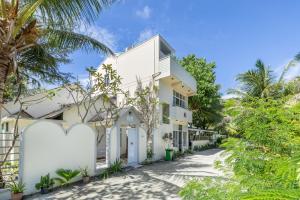 a white house with palm trees in front of it at Three Hearts in Fulhadhoo