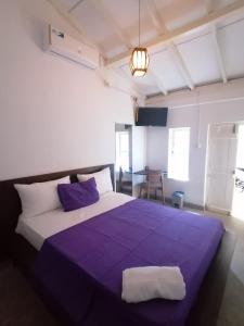 a bedroom with a bed with a purple blanket at Villa Fernando Resort in Chilaw