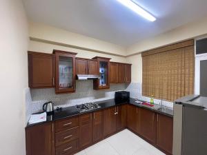Wellawatte Apartment في كولومبو: مطبخ مع خزائن خشبية وقمم منضدة سوداء