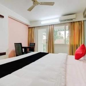 Schlafzimmer mit einem großen weißen Bett und einem roten Kissen in der Unterkunft AEC Travel and Leisure Solution Pvt Ltd in Alappuzha