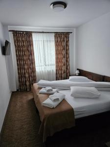 2 łóżka w pokoju hotelowym z ręcznikami w obiekcie Pensiunea Magura Ocnei w mieście Târgu Ocna