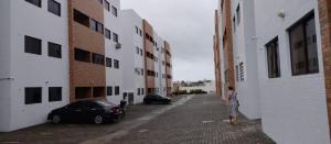 un hombre parado en un callejón entre dos edificios en Apto familiar c/ piscina, próx as praias reg Sul en João Pessoa