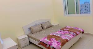 uma cama num quarto branco com uma janela em marena em Ajman