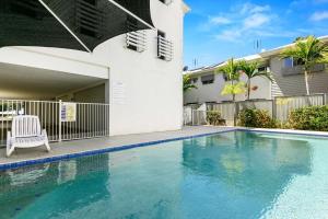 a swimming pool in front of a house at Beachfront Nirvana in Urangan