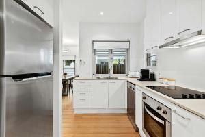 a kitchen with white cabinets and a stainless steel refrigerator at Beachfront Nirvana in Urangan