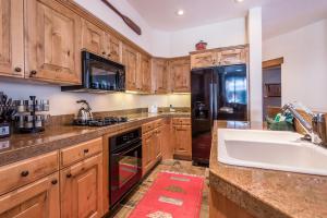 cocina con armarios de madera y nevera negra en Westridge Condo 27 - Cozy Condo Walk to Bald Mt and Downtown Ketchum en Ketchum