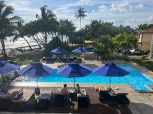 a group of people sitting under blue umbrellas by a pool at IMAGINE Villa Hotel in Mirissa