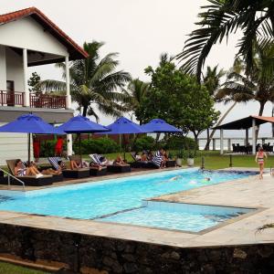 uma piscina com cadeiras e guarda-sóis azuis em IMAGINE Villa Hotel em Mirissa