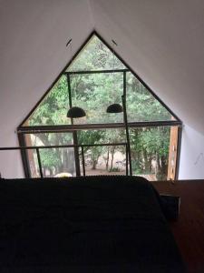 uma grande janela num quarto com uma cama em Chalé da Colina Florianópolis em Florianópolis