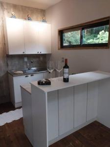 a kitchen with white cabinets and two wine glasses at Chalé da Colina Florianópolis in Florianópolis