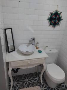 uma casa de banho branca com um lavatório e um WC em Chalé da Colina Florianópolis em Florianópolis