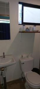 a bathroom with a white toilet and a sink at Container home 25 min Jaco y Herradura in Tarcoles
