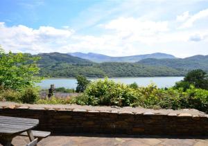 a view of a lake with a bench and mountains at Bryn Hyfryd in Penmaenpool