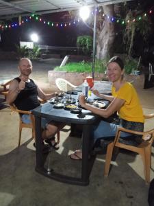 Un uomo e una donna seduti a un tavolo con del cibo di UK homestay a Malwan